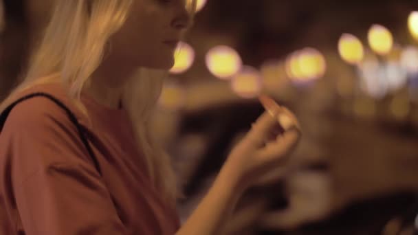 Mujer aplicando brillo de labios afuera por la noche — Vídeos de Stock