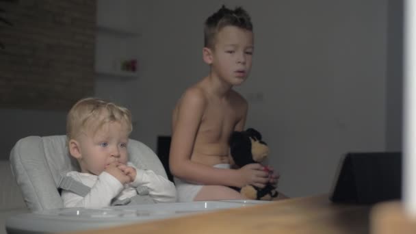 Sömnig pojke och hans lilla syster tittar på tecknad film på Tablet PC på morgonen — Stockvideo