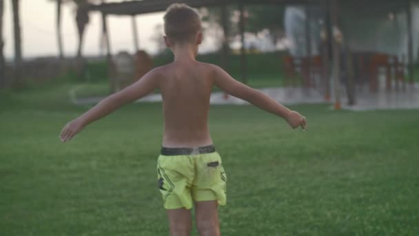 Child getting shower with automatic garden sprinkler — Stock Video