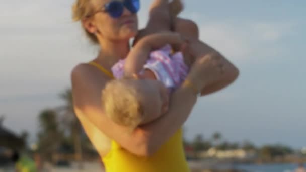 Mama maken baby dochter lachen. Familie ontspannen op het strand — Stockvideo