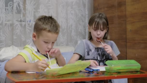 Niños haciendo dibujos y comiendo dulces — Vídeos de Stock