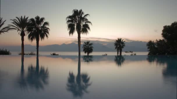 Timelapse de la noche en el resort. Piscina, palmeras y escena con mar y montaña — Vídeos de Stock