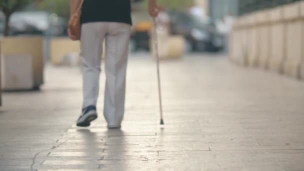 Oudere vrouw met stok wandelen in de straat — Stockvideo