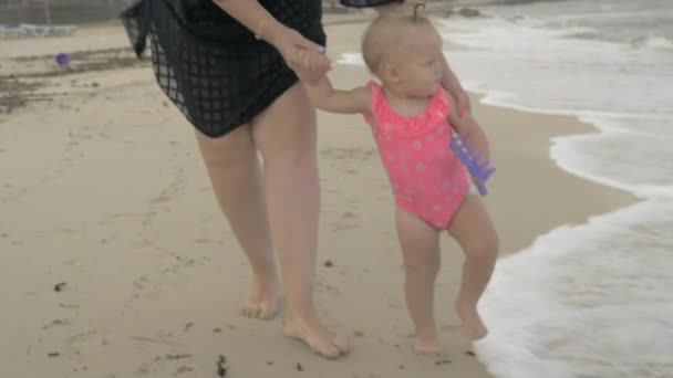 Mum with baby daughter walking barefoot on the beach — Stock Video