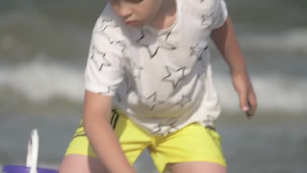 Niño jugando con arena en la playa — Vídeo de stock
