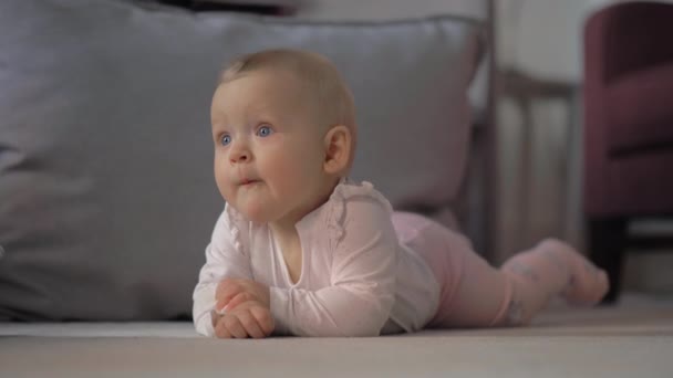 Retrato interior de la niña acostada sobre el vientre — Vídeos de Stock