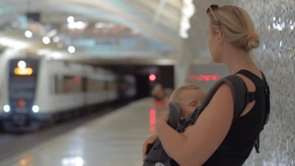地下鉄の駅で眠っている赤ちゃんを持つ女性 — ストック動画