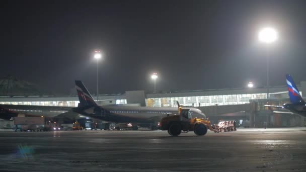 谢列梅捷沃机场 d 航站楼, 有飞机和雪犁拖拉机。夜景 — 图库视频影像