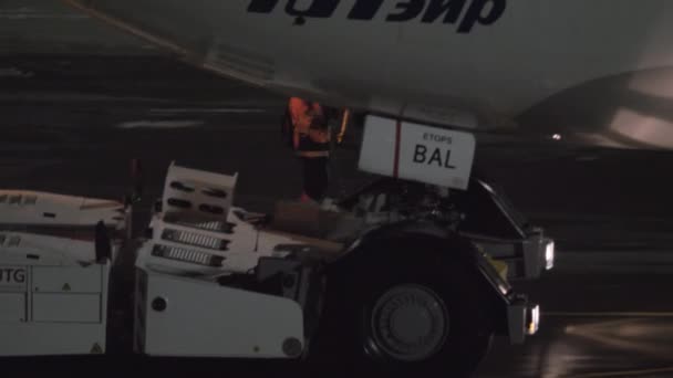 Pushback van Utair vliegtuig 's nachts. Uitzicht met cockpit en piloot in de cabine — Stockvideo