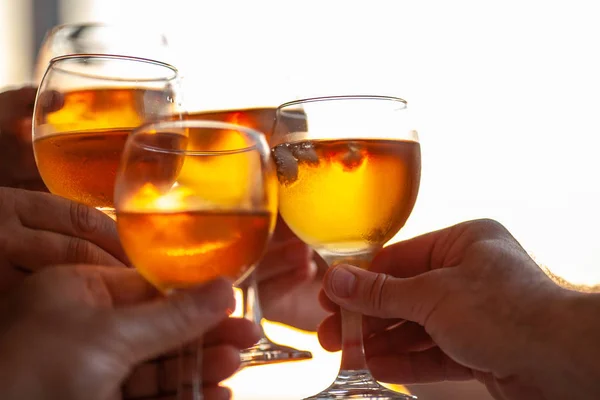 Vier handen geproost vier veld glazen met een drankje, gekleurd in goud door de achtergrond instelling zon — Stockfoto