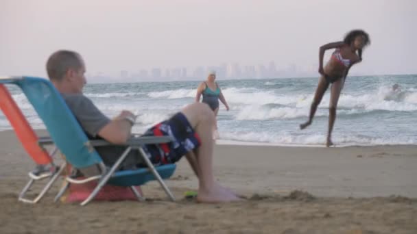 Pessoas na praia da cidade com mar ondulado em Valência, Espanha — Vídeo de Stock