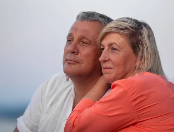 A middle aged couple sitting close to each other and looking into the distance, smiling — Stock Photo, Image