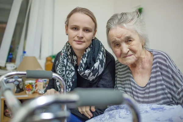 A portrait of two women, young and elderly, sitting close to each other — Stock Photo, Image