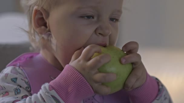 Baby girl having a snack with apple — Stock Video
