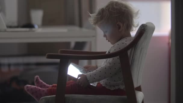 Маленькая девочка смотрит мультики на планшетном компьютере дома — стоковое видео