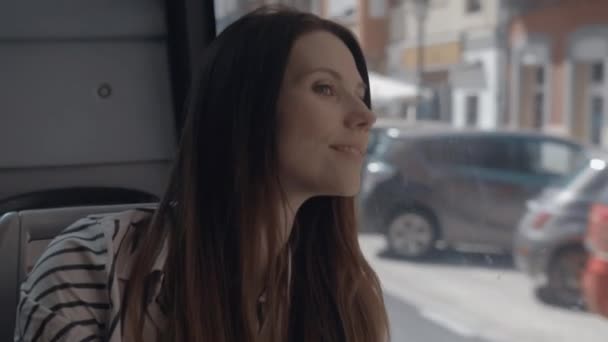 Una chica de pelo largo sentada en un autobús y mirando por la ventana — Vídeo de stock