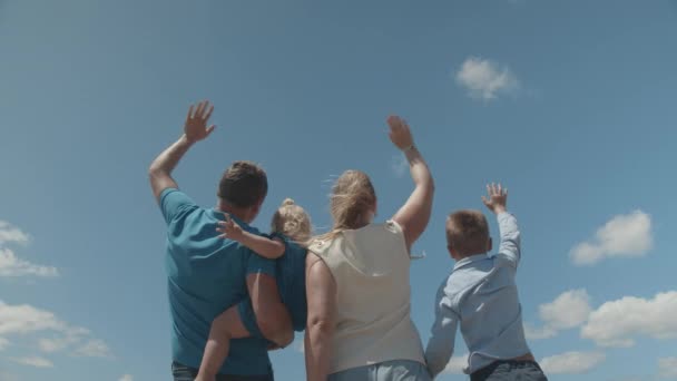 Una joven familia saludando a un avión, volando por encima — Vídeo de stock