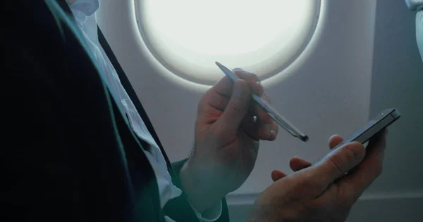 Επιχειρηματίας που χρησιμοποιεί έξυπνο τηλέφωνο κατά τη διάρκεια της πτήσης — Φωτογραφία Αρχείου