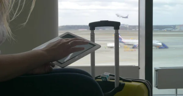 Женщина, ожидающая полета с планшетным ПК — стоковое фото
