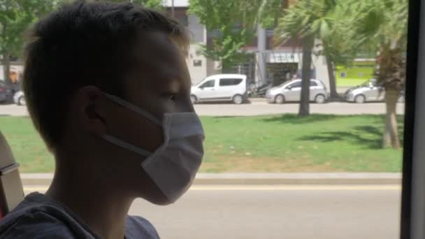 Busfahrt durch die Stadt. Kind trägt Gesichtsmaske — Stockvideo