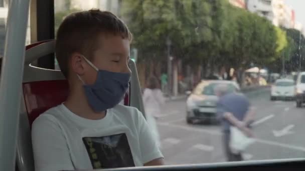 Дев'ятирічний хлопчик з маскою для обличчя в автобусі — стокове відео