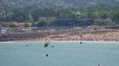 GIJON, İSPAN - 27 HAZİRAN 2025: İki sarı itfaiye helikopteri halka açık gösteri sırasında sahilde su indirme manevrası yapıyor