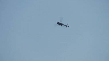 Hava manevrası sırasında açık mavi gökyüzüne karşı tek başına uçan tek bir askeri helikopter.