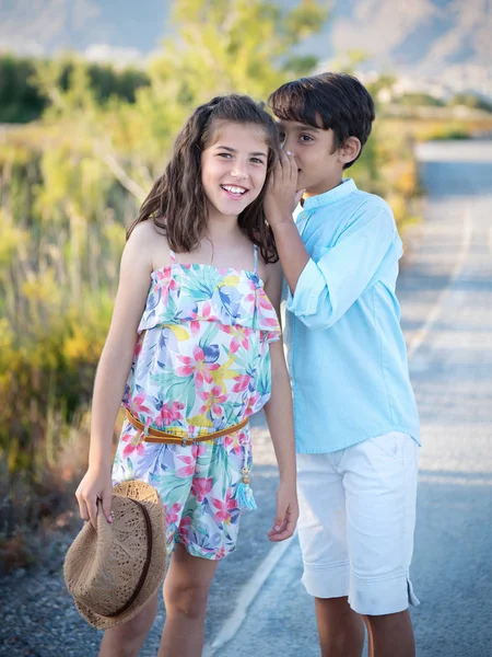Vidám fiú és a lány suttogva természet háttér. — Stock Fotó