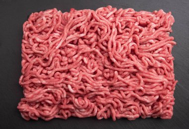 Siyah plaka ve ahşap arka plan üzerinde taze kıyılmış domuz.