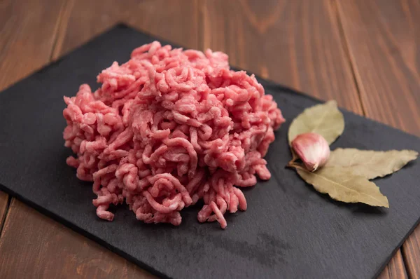 Fresh minced pork on black plate and wooden background. — Stock Photo, Image