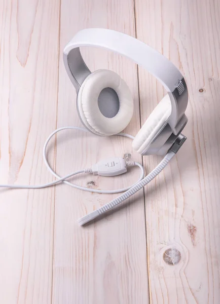 Белые наушники с микрофоном для воспроизведения на светлом деревянном фоне — стоковое фото
