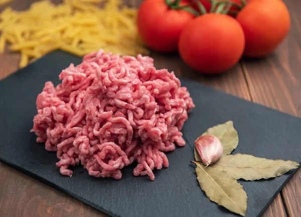 Raw pork mince on black plate and wooden background — Stock Photo, Image