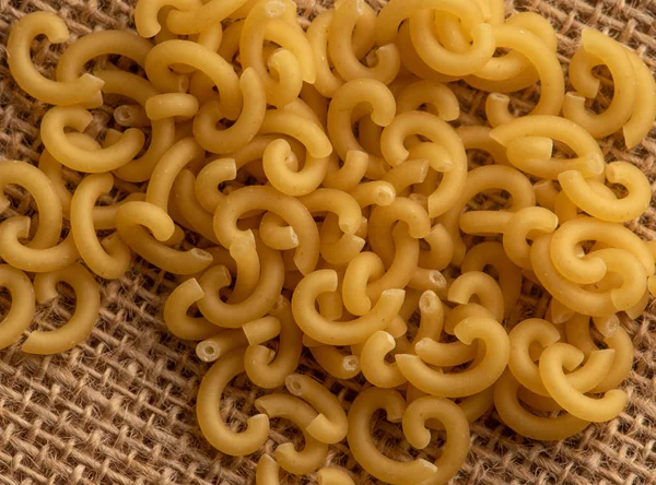Small pasta close-up on the burlap. Carbohydrate food. — Stock Photo, Image