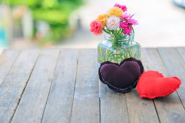  Cam doğa arka plan ile ahşap masa üzerinde moss rose çiçekli kahverengi ve kırmızı yastık.