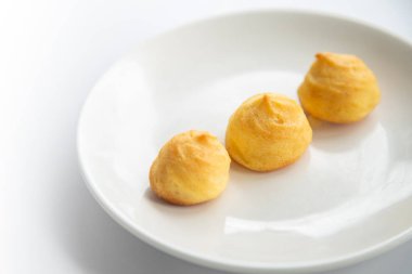 Ev yapımı bir Choux (Eclair) grubunu beyaz bir masada beyaz bir tabakta kapat 