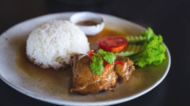 Siyah masada beyaz tabakta kızarmış tavuklu pilav..