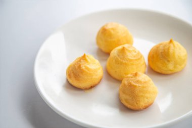 Ev yapımı bir Choux (Eclair) grubunu beyaz bir masada beyaz bir tabakta kapat 