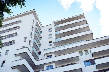 Mavi gökyüzü olan güneşli bir günde modern apartman binaları. Modern bir apartmanın cephesi