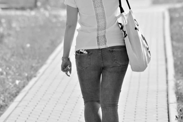 The back view of a girl walking down the street. Black and white.