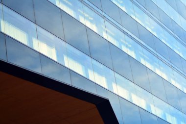 Gökyüzü ve bulutlar üzerinde yansıtılmış cam ile bir bina yansıtan