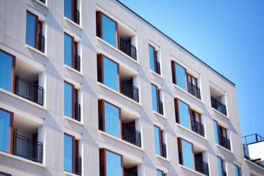 Mavi gökyüzü olan güneşli bir günde modern apartman binaları. Modern bir apartmanın cephesi