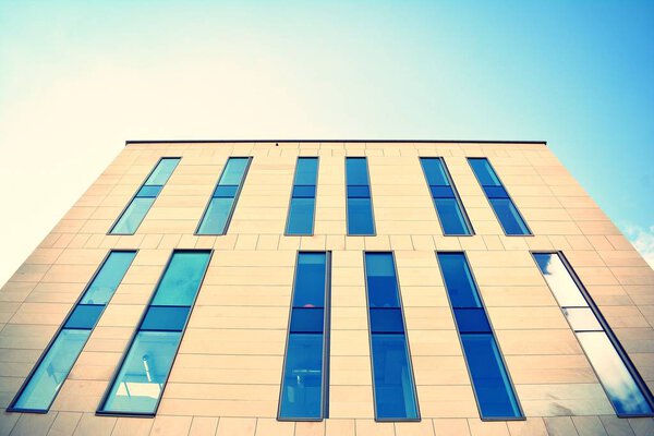 Modern office building on a clear sky background. Retro stylized colorful tonal filter effect