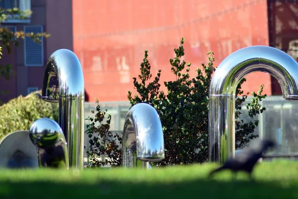 Public art installation in front modern building.Decorative stainless steel pipes