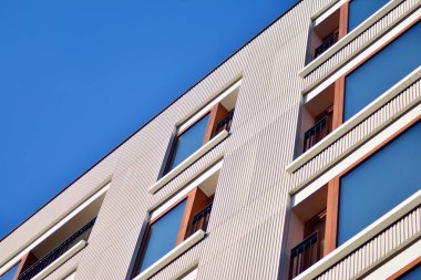 Mavi gökyüzü olan güneşli bir günde modern apartman binaları. Modern bir apartmanın cephesi