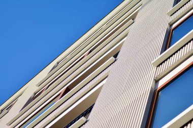 Mavi gökyüzü olan güneşli bir günde modern apartman binaları. Modern bir apartmanın cephesi