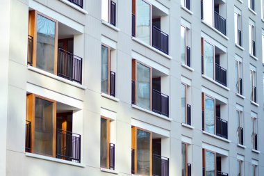 Mavi gökyüzü olan güneşli bir günde modern apartman binaları. Modern bir apartmanın cephesi