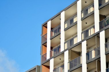 Mavi gökyüzü olan güneşli bir günde modern apartman binaları. Modern bir apartmanın cephesi