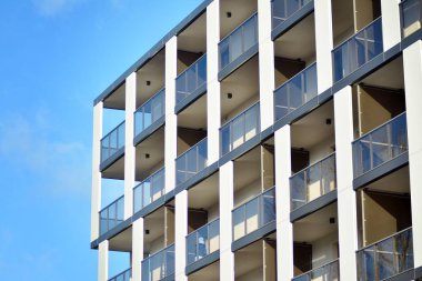 Mavi gökyüzü olan güneşli bir günde modern apartman binaları. Modern bir apartmanın cephesi