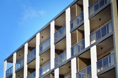 Mavi gökyüzü olan güneşli bir günde modern apartman binaları. Modern bir apartmanın cephesi