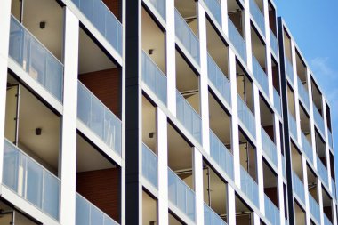 Mavi gökyüzü olan güneşli bir günde modern apartman binaları. Modern bir apartmanın cephesi